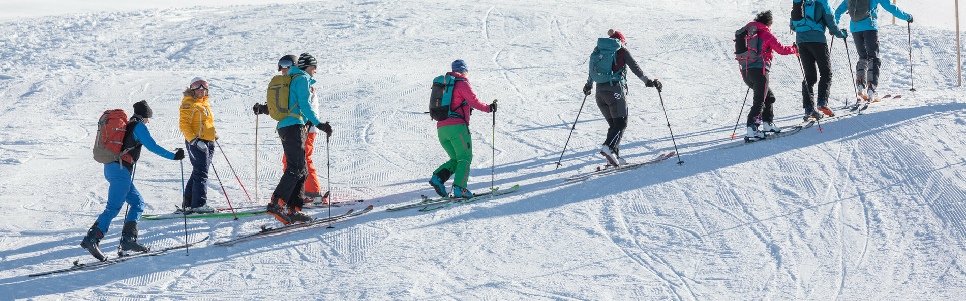 Gruppe von Skitourengeher*innen quert die Skipiste.