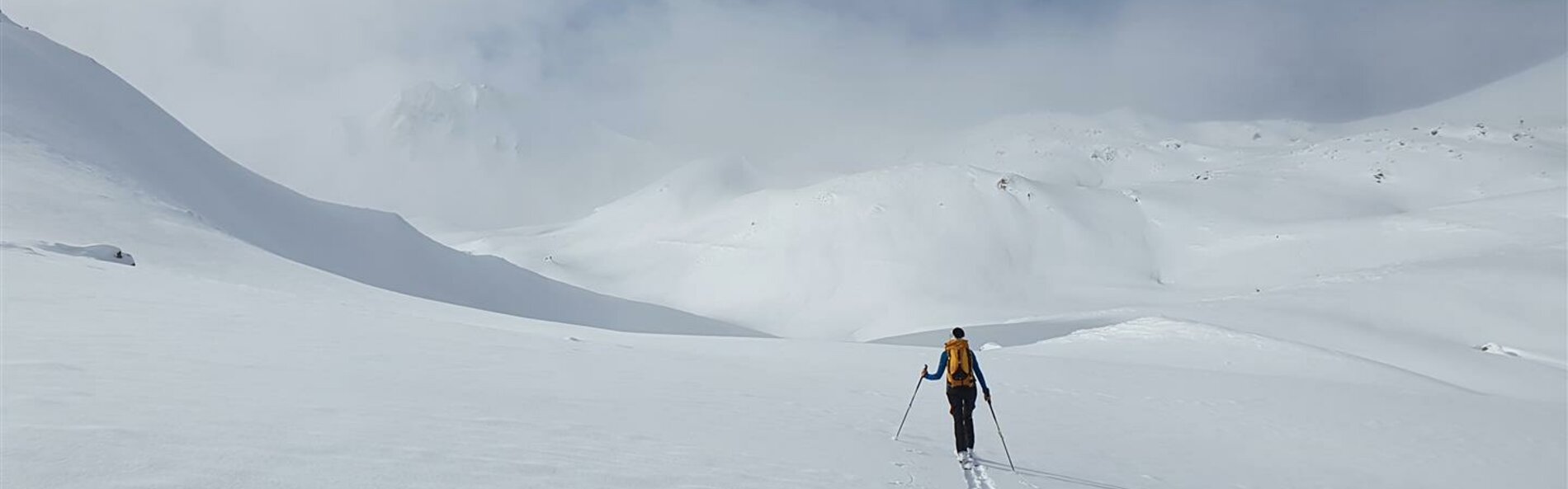 Skitourengeher*in beim Queren eines tiefverschneiten Schneefelds © Land Tirol