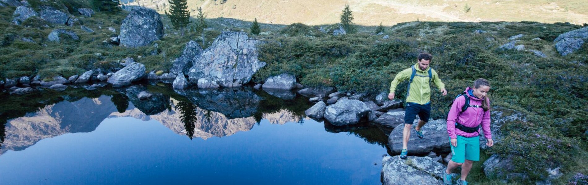 Bergsteiger bewegen sich an einem Teich vorbei.