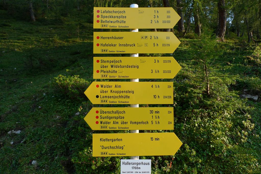 Gelber alpiner Wegweiser mit mehreren Richtungs- und Zeitangaben für Wanderziele im Karwendelgebirge.